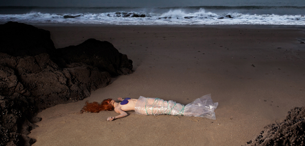 Une femme emballée façon petite sirène, morte sur une plage