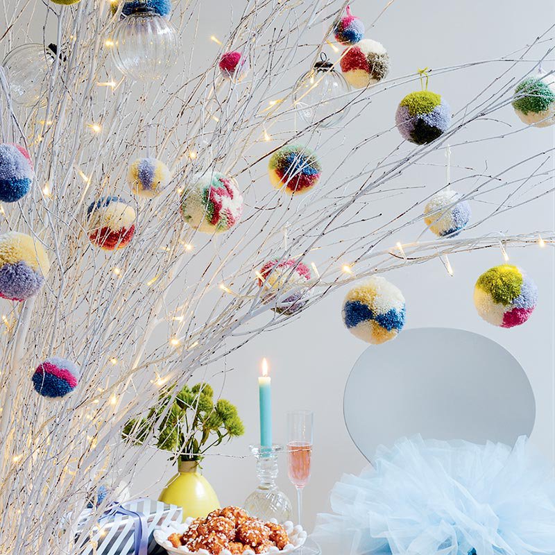 Pompons multicolors sur des branches en intérieur