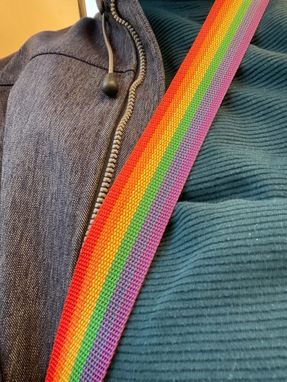 A close-up of two different fabrics with a rainbow-colored strap across them.