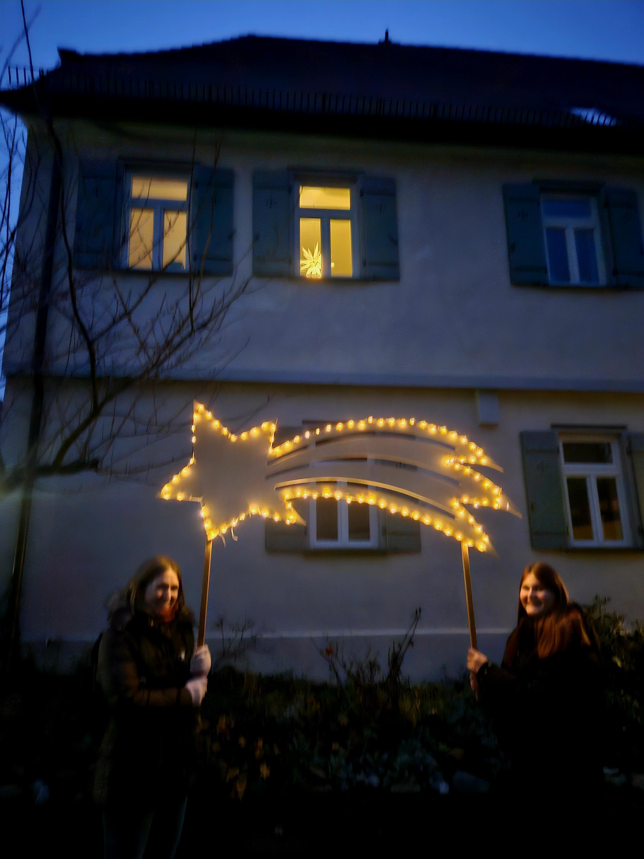 Leuchtender Stern mit Schweif gehalten an zwei Stäben