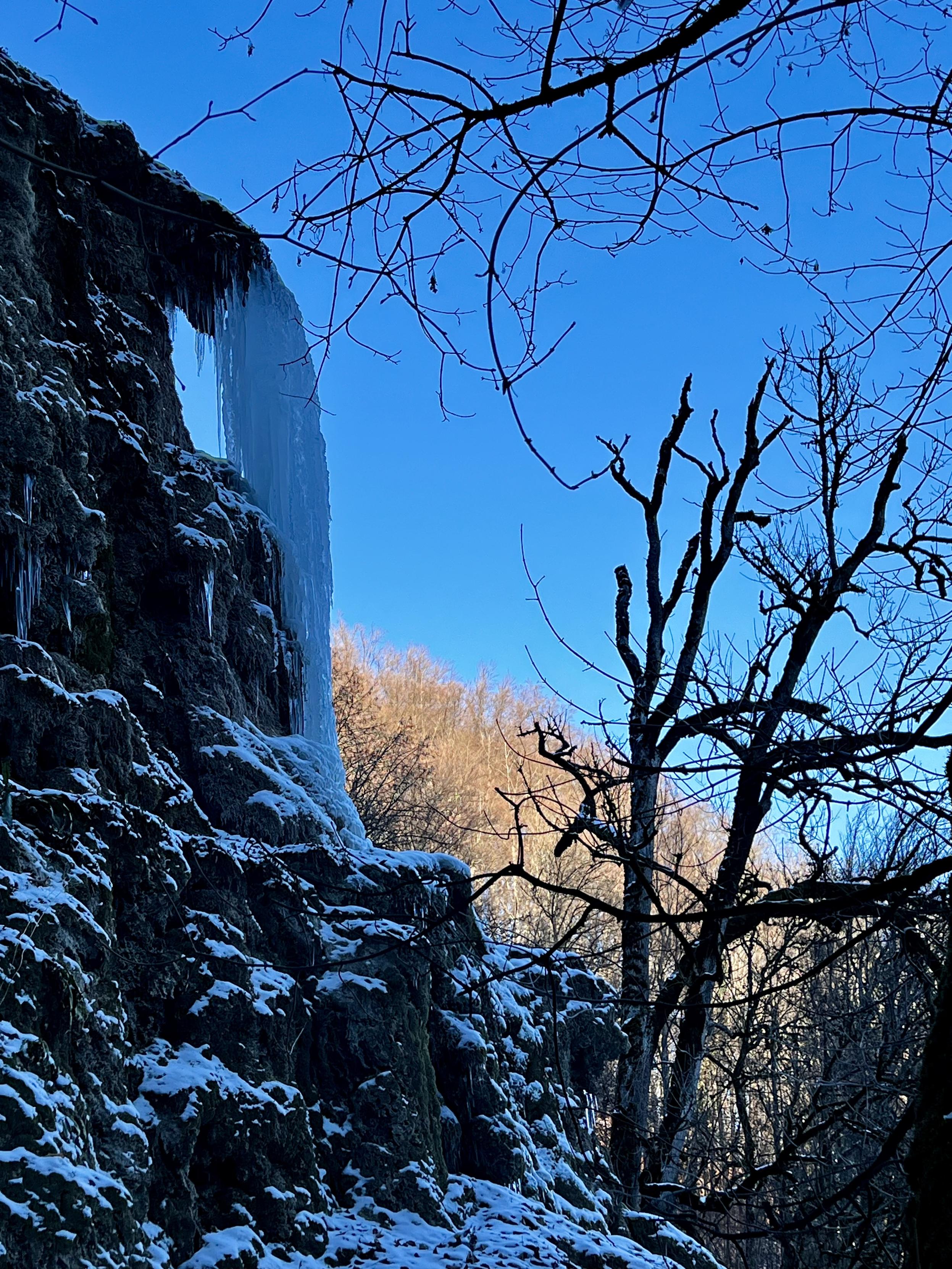 Ein zu Eis erstarrter Wasserfall vor winterlicher Kulisse