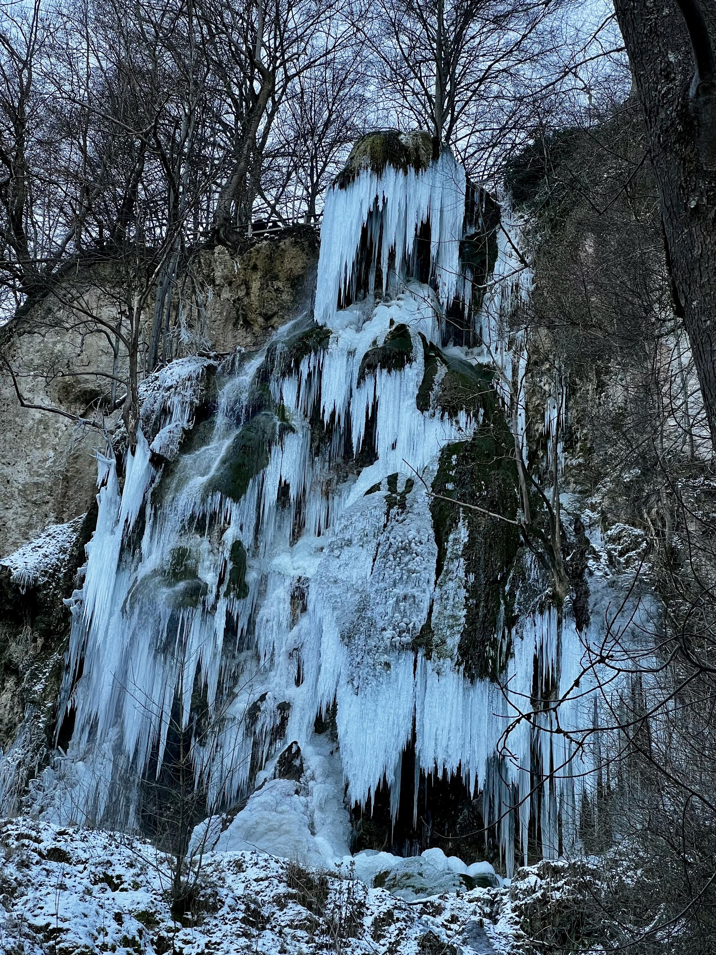 Ein zu Eis erstarrter Wasserfall vor winterlicher Kulisse