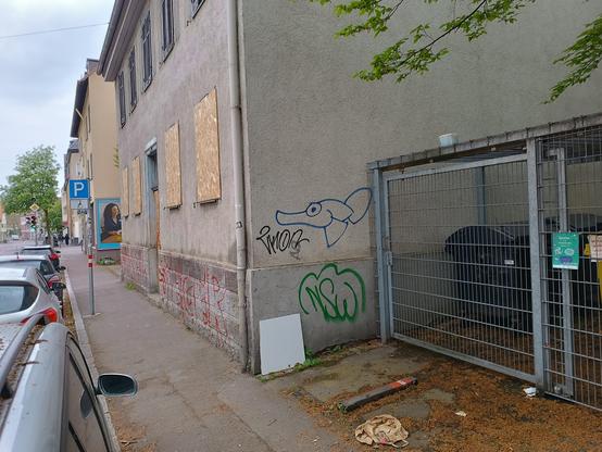 man sieht einen als schwarzen Minimalumriss gesprayten Fisch-Charakter von etwa 1.20 zu 70  an einem zugesperrten Haus in Cannstatt