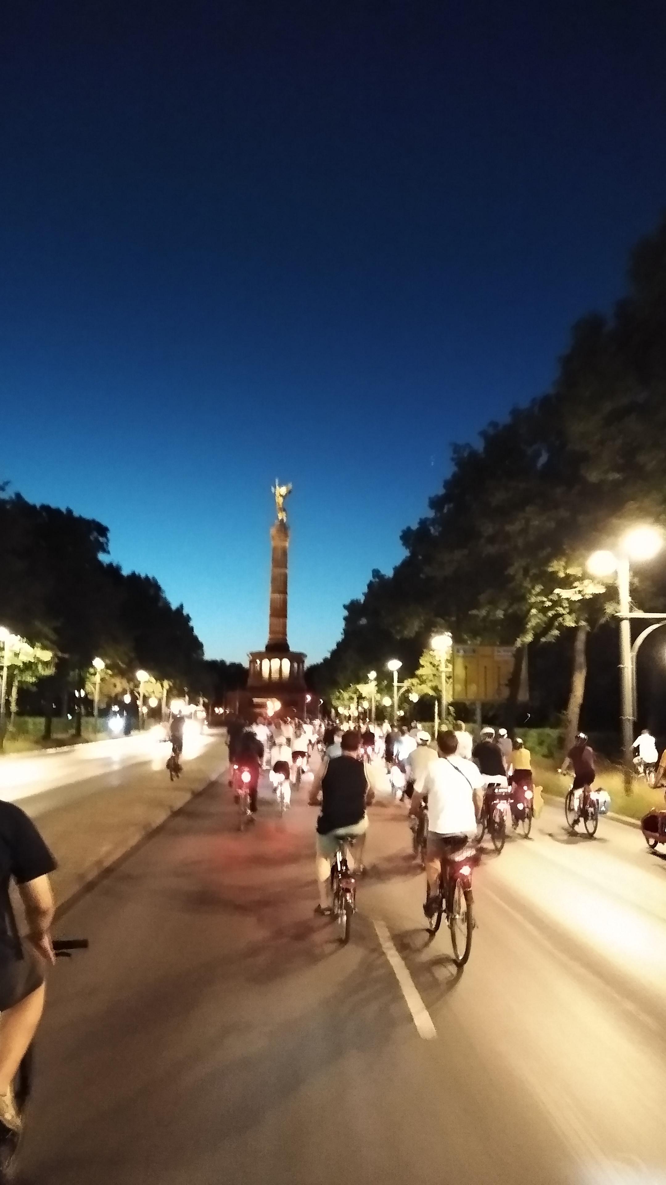 Radfahrende fahren auf die nächtliche Siegessäule zu