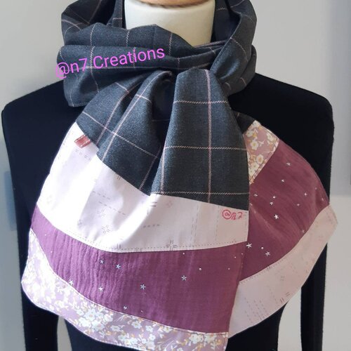 Echarpe en tissu gris à grands carreaux aux extrémités roses.