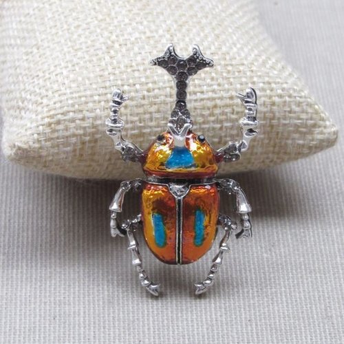 Broche bijou insecte coléoptère style scarabée acier orange et bleu.