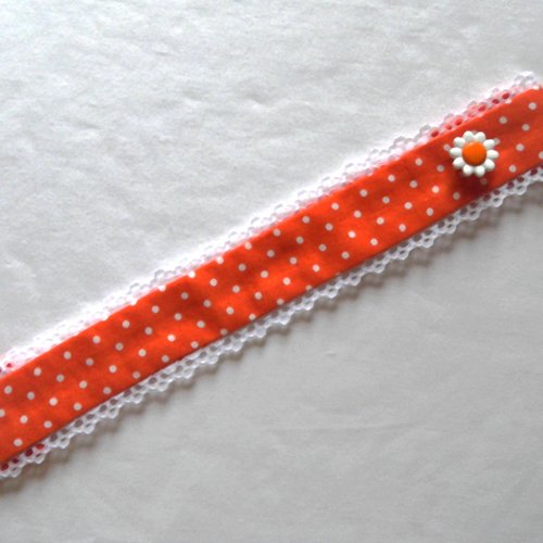 Bracelet textile en tissu liberty orange à petits pois blancs, bordé dentelle , fermeture bride et bouton fleur .