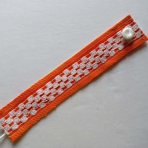 Bracelet manchette en tissu couleur orange et dentelle cirée blanche.