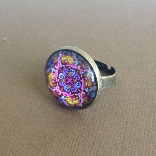 Bague en métal couleur bronze et cabochon motif volutes violettes et roses 