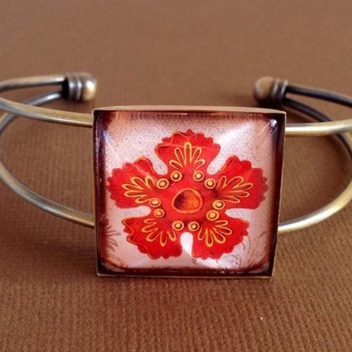 Bracelet en métal couleur bronze et cabochon de verre carré motif étoile de mer sur fond blanc 