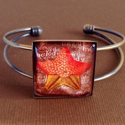 Bracelet en métal couleur bronze et cabochon de verre carré motif étoile de mer jaune et orangée. 