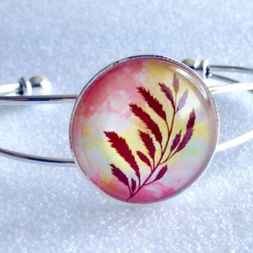 Bracelet rigide métal argenté et cabochon de verre motif feuille d'automne sur fond rose jaune 