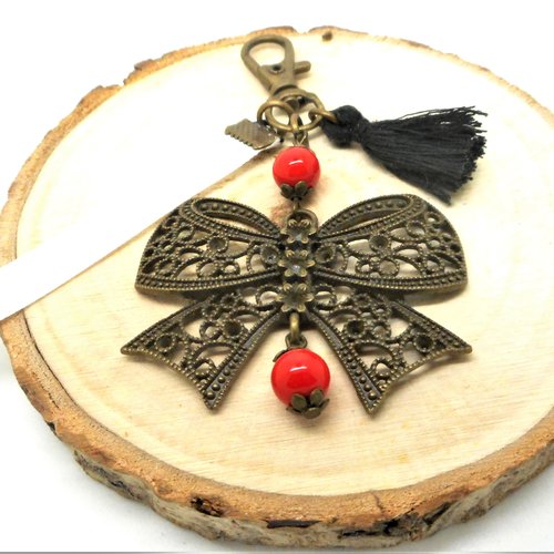 Bijou de sac noeud bronze perles rouges, ruban blanc et pompon noir