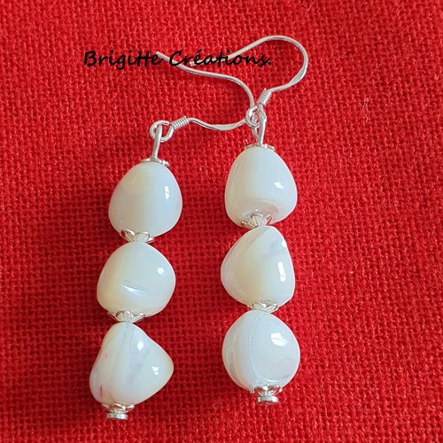 Boucles d'oreilles en nacre blanche montées sur des crochets d'oreilles en argent.