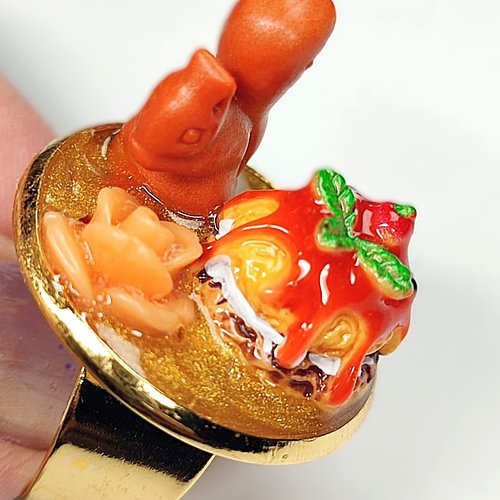 Bague les biduleries en résine écureuil avec un gâteau et une fleur sur fond paillette doré support doré
