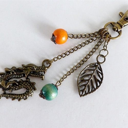 Porte clé perle de bois verte et orange , breloques feuilles et dragon bronze.