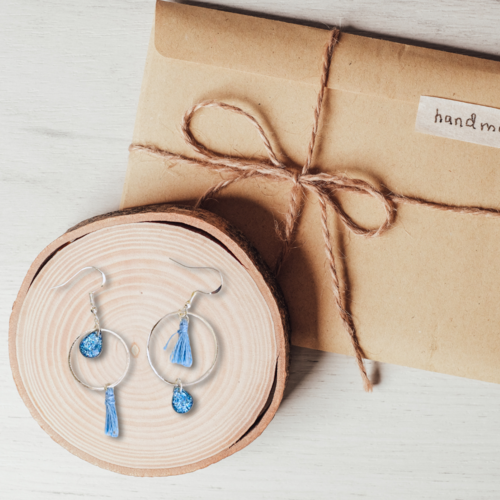 Boucles d'oreilles petites créoles argenté agrémentées d'une goutte en résine transparente aux paillettes bleues et ses pompons