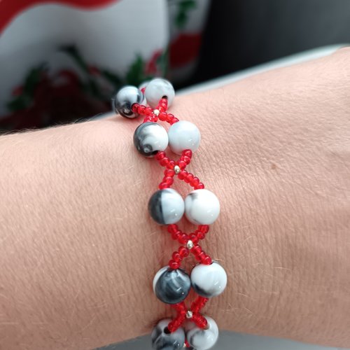 Bracelet fait main en perles de rocaille rouges et perles marbrées noir et blanc, design graphique croisé