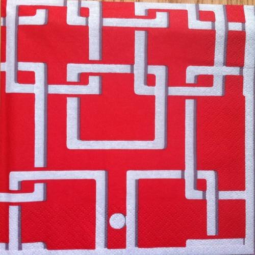 Serviette en papier motif graphique carrés blancs enchevétrés sur fond rouge 