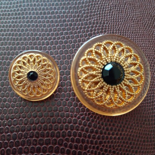 Bouton socle plastique avec une rosace en doré incrustée et au centre un strass noir, diamètre 16 mm.