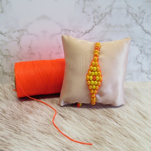Bracelet micro macramé fils orange hyacinth et perles de rocaille orange clair et foncé jaune tissé à la main forme losange.