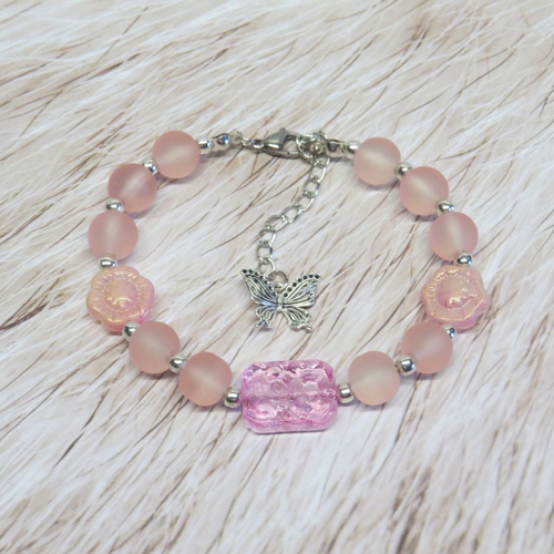 Bracelet grande perle de verre rectangle gravé floral rose transparente et sa petite breloque papillon en métal argenté.