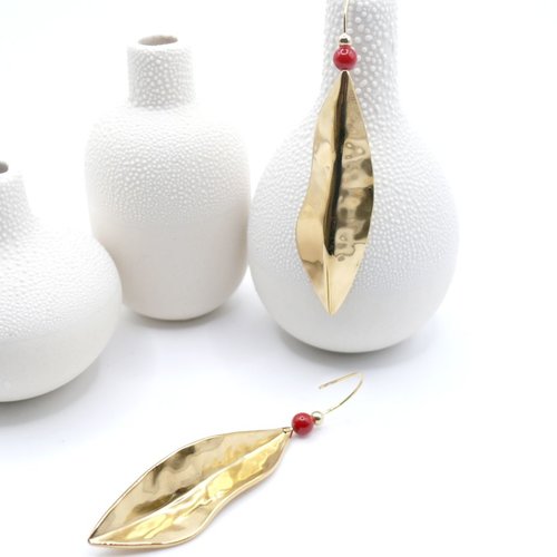Longues boucles d’oreilles en acier inoxydable finition 18k, ornées d’une feuille stylisée et de perles rouges.