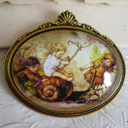 Broche en métal doré  "trois petits elfes des fleurs jouent avec un escargot"