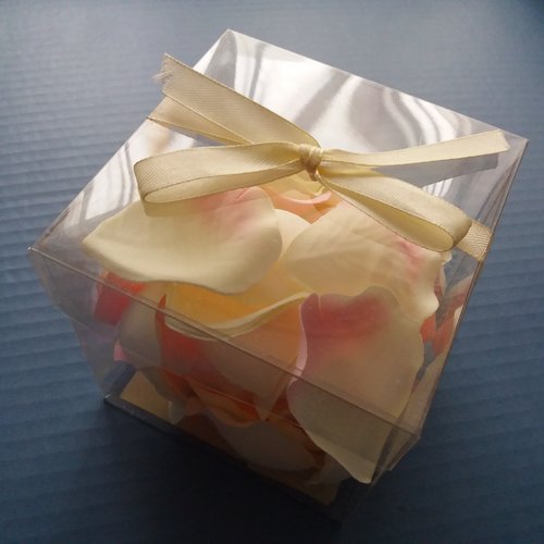 Pétales de roses en tissu blancs et rose dans son emballage avec noeud