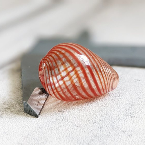 Une perle en verre soufflé forme goutte transparent et orange fabriquée artisanalement