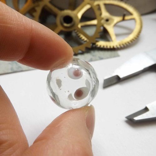 1 perle de verre filée au chalumeau, transparente avec des "yeux", blanc et rose, diamètre 1,9 cm