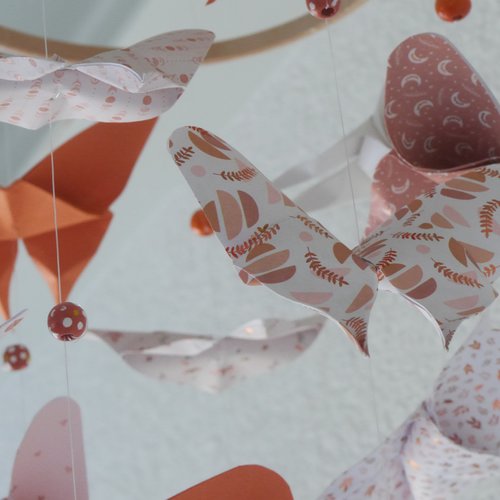Mobile pour bébé : papillons en origami et perles en bois suspendus à un anneau en bambou