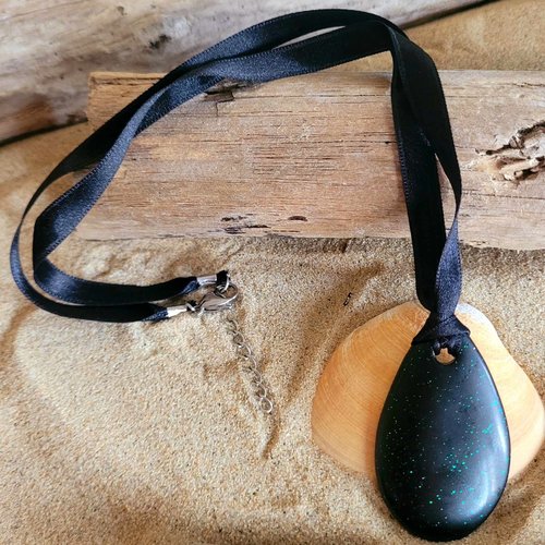 Un collier en résine noir avec paillette irisé monté sur ruban satin noir
