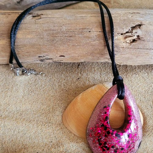 Un collier en résine noir et paillettes fuchsia monté sur cordon satiné noir