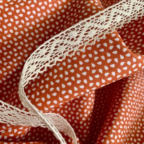 Tissu en coton, fond couleur piment d'espelette, décor grains de riz, de 3 mm,  vente par 25 cm/160 cm