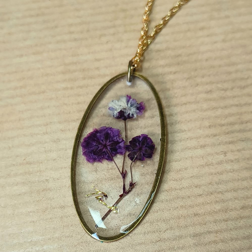 Collier avec pendentif ovale en résine et fleurs séchées violettes et blanches