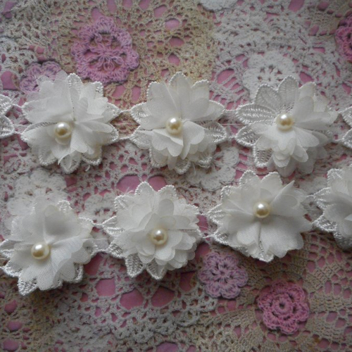 Fleurs blanches en mousseline sur de la dentelle avec une perle blanche, par 4 fleurs, de 5,00 de diamètre.