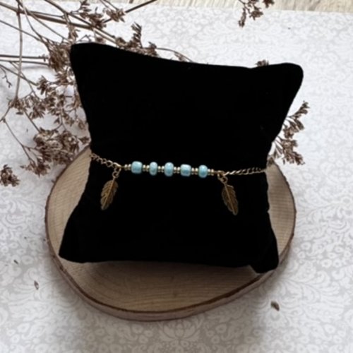 Bracelet doré, plumes et perles bleues