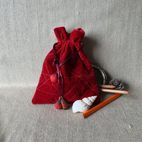 Luxueuse pochette en velours de soie rouge légèrement brodée.