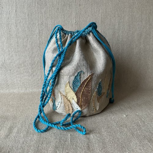 Sac boule polochon en lin métallisé doré brodé d’un feuillage de soie or pale, vieil or et écrue et coton turquoise.