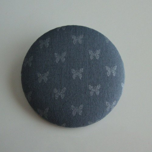 Badge recouvert de tissu france duval orageux motifs papillons argentés. ø : 45 mm.