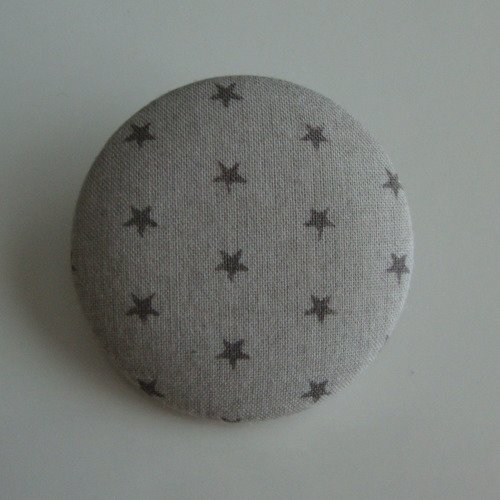 Badge recouvert de tissu frou frou argile motifs étoiles foncées. ø : 38 mm.