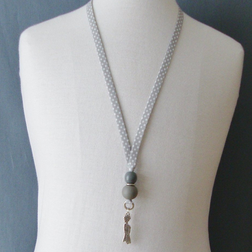 Collier biais en tissu pois blancs sur fond gris, perles en bois grises, personnage en métal argenté.