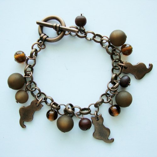 Bracelet breloques : chats en métal couleur cuivre, perles polaris et en verre pressé marron.