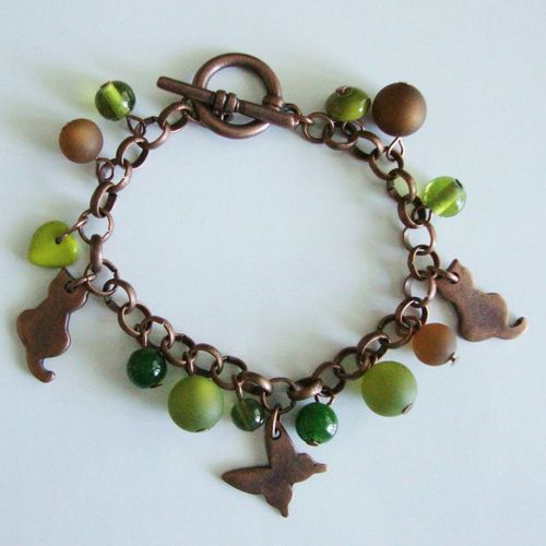 Bracelet breloques : chats et papillon en métal couleur cuivre, perles polaris et en verre pressé marron-vert.