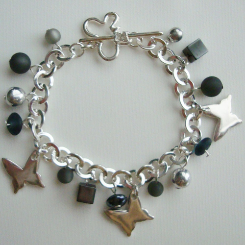 Bracelet breloques : papillons, perles polaris "jet hematite" et "black diamond", perles en verre pressé, fermoir t en métal argenté.