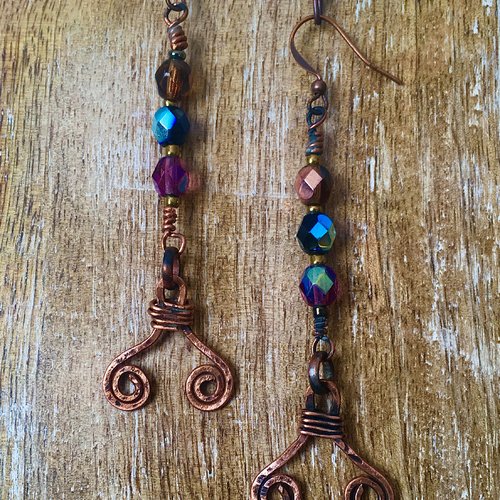 Boucles d'oreilles pendantes en perles à facettes parme et pièces en cuivre martelé.