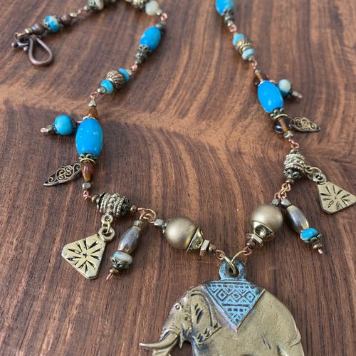 Collier mi-long ethnique avec une supension éléphant, des perles dorées, des perles turquoises sur chaîne en cuivre.