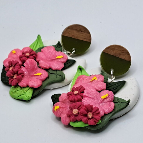 Boucles d'oreilles argile polymère fleurs d'hibiscus roses sur fond blanc et feuilles puces bois naturel et vert