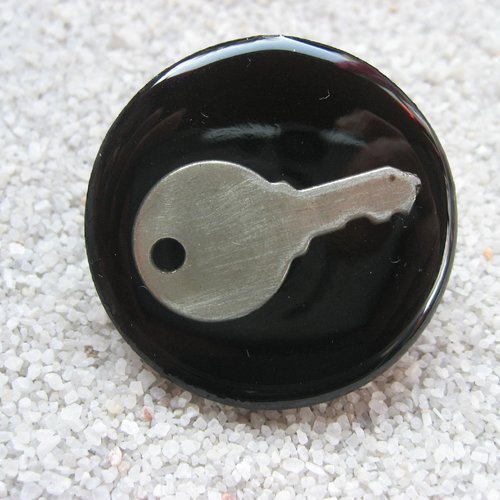 Grande bague fantaisie, la clé du bonheur, sur fond noir en résine / diamètre 35mm 
